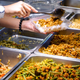 Person's hands serving from a buffet
